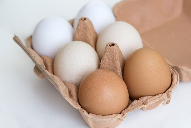 White, tan, and brown eggs in a carton