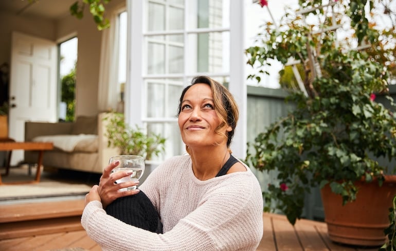 Menopausal woman sitting outside hydrating to help with vaginal dryness