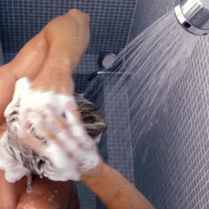 Man washing hair in shower with a filter to clear out chemicals