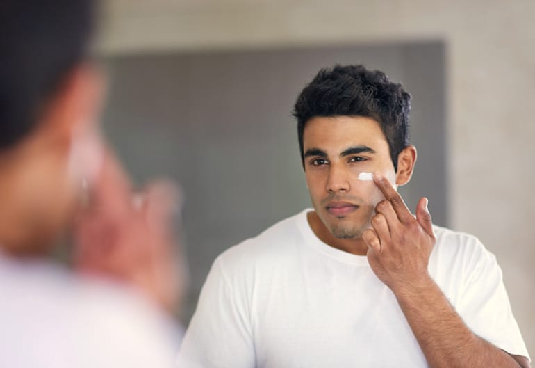 Man applying mineral sunscreen to his oily, acne-prone skin