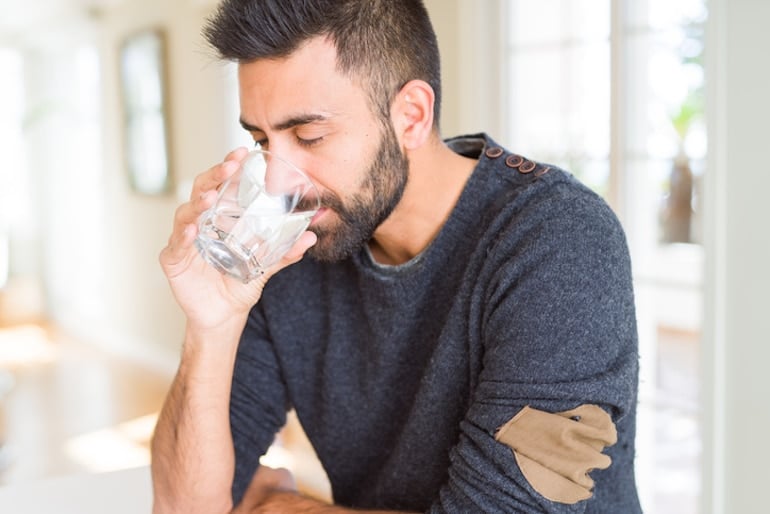 Man drinking filtered tap water to stay hydrated and healthy