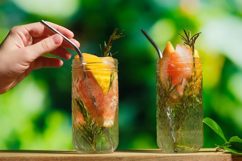 Person putting straw into a glass of hard seltzer with added fruit for health benefits