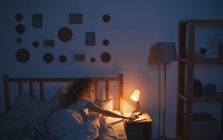 Woman turning off light to improve her sleep and immunity