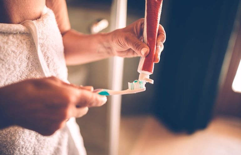 Woman applying toothpaste to remove stains and discoloration