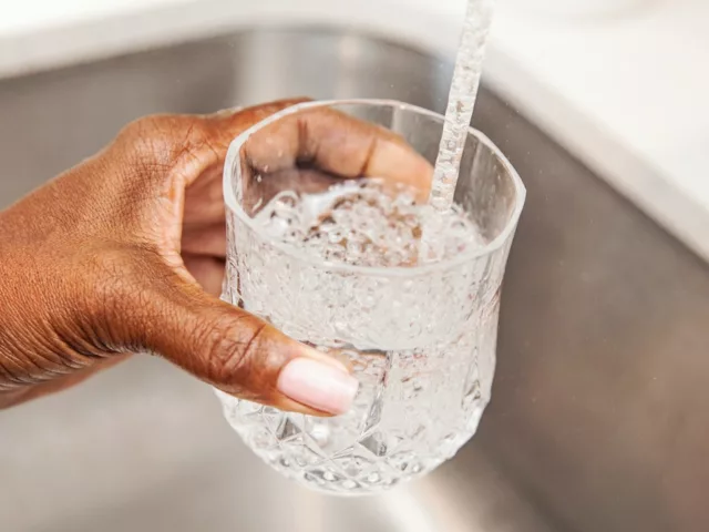 Woman filling glass of tap water from sink