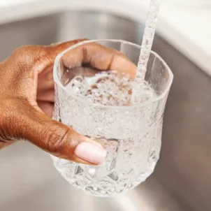 Woman filling glass of tap water from sink