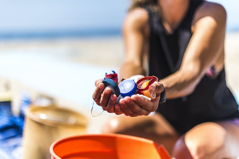 Woman holding bottle caps that would end up as plastic pollution in the ocean