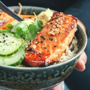 Person eating a salmon, one of the healthiest fish to eat, in a poke bowl