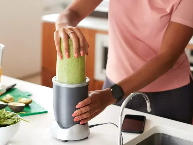 Woman making a green smoothie for their health benefits