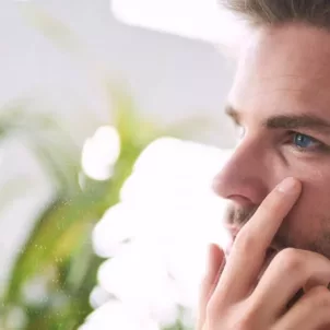 Man investigating wrinkles in mirror, wondering about the best time to take collagen