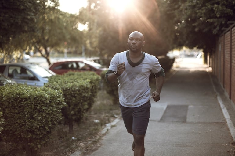 Man running on street sweating through his shirt