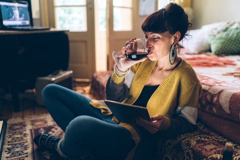 Woman drinking red wine, which can cause teeth to stain and yellow