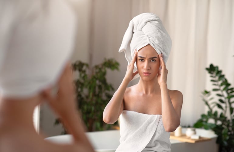 Woman out of shower looking at collagen loss via wrinkles