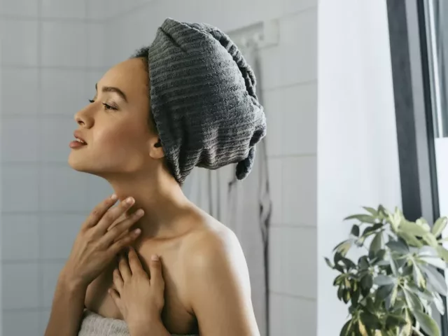 Woman out of shower looking at her complexion after using probiotic skincare