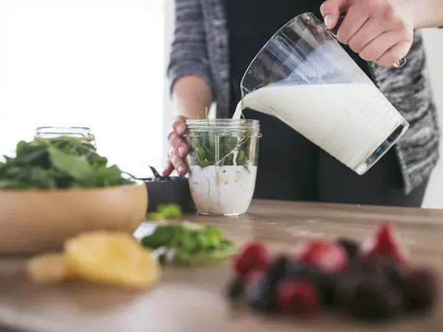 Pouring milk into blender for a low FODMAP smoothie recipe for breakfast