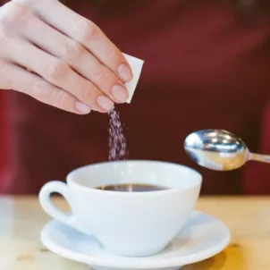 woman putting sweetener in coffee