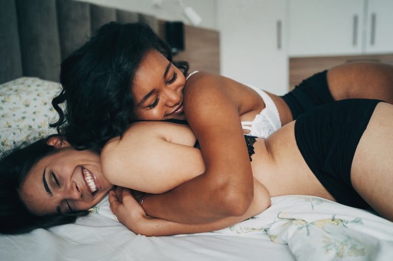 two women laughing in bed