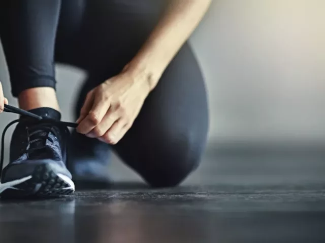 woman at gym tying sneaker