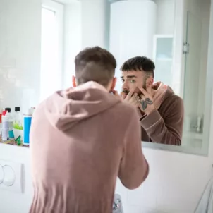 Man popping a pimple in the mirror, hoping to heal the inflammation