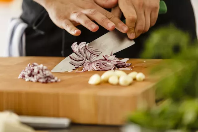 Man chopping garlic and onions, both of which contain sulfur and FODMAPs