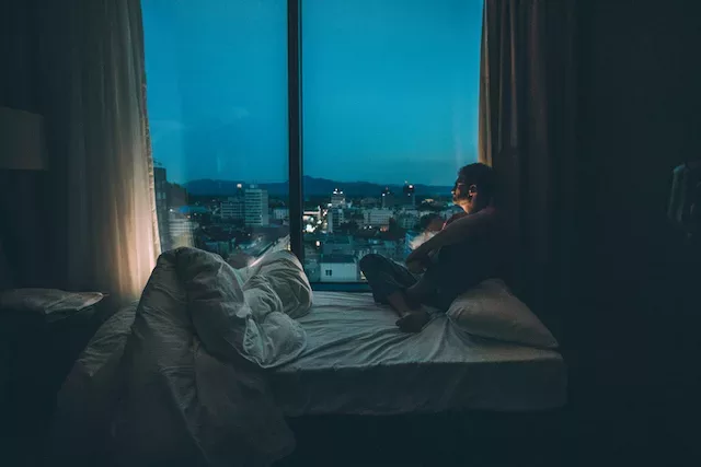 Man with jet lag looking out of hotel window