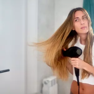 Woman with long dry hair using a blow dryer