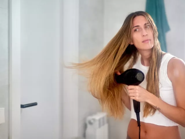 Woman with long dry hair using a blow dryer