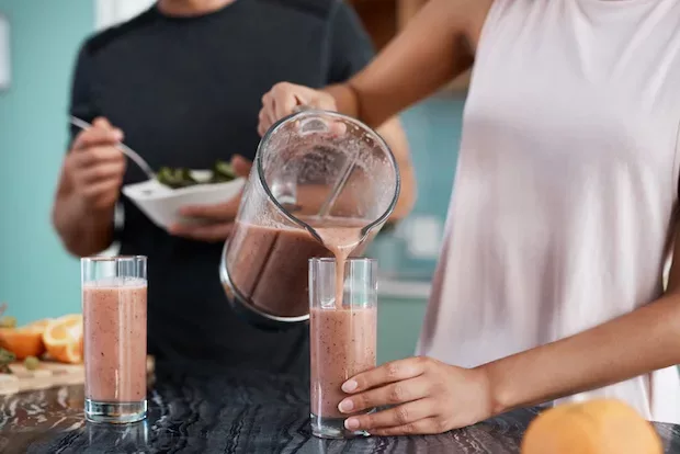 Active couple pouring smoothies to lose weight after exercise