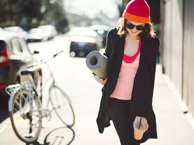 Woman walking out of yoga with a smoothie to illustrate the 70/30 diet and exercise plan