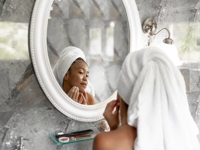 Woman looking in the mirror investigating if zinc for acne is helping