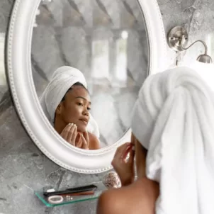 Woman looking in the mirror investigating if zinc for acne is helping