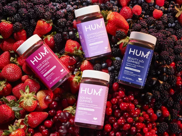 Clean and clinical HUM gummy vitamins on a bed of fruit