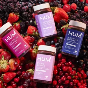 Clean and clinical HUM gummy vitamins on a bed of fruit