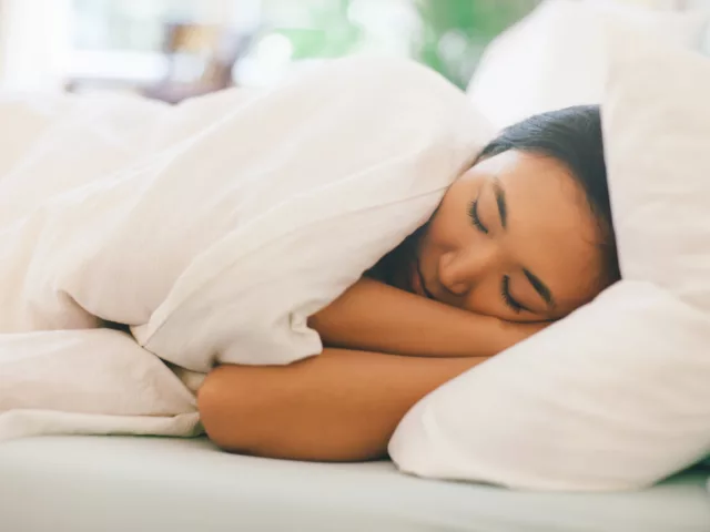 Woman sleeping on her left side, which is one of the best sleeping positions for digestion