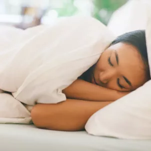 Woman sleeping on her left side, which is one of the best sleeping positions for digestion