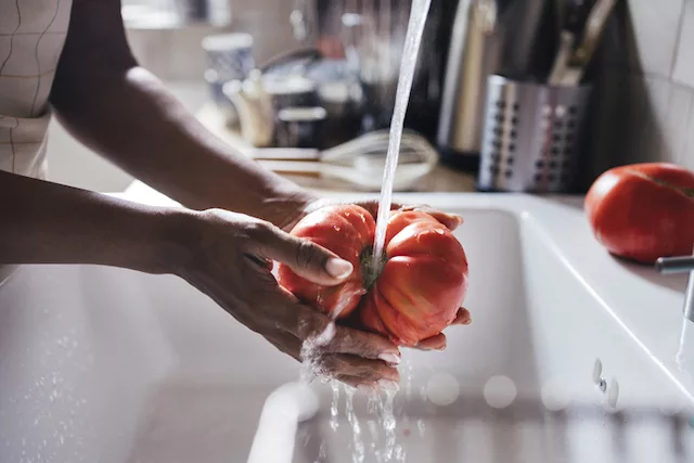 Woman washing a tomato, one of the best foods with prebiotics