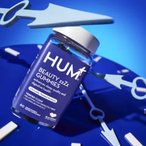 HUM Beauty zzZz Gummies for sleep and digestion, with a clock in background