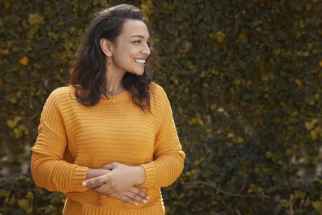 Happy woman holding her stomach to demonstrate a diverse gut from prebiotics and probiotics