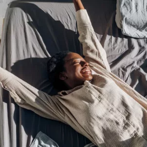 Happy woman stretching in bed after getting beauty sleep