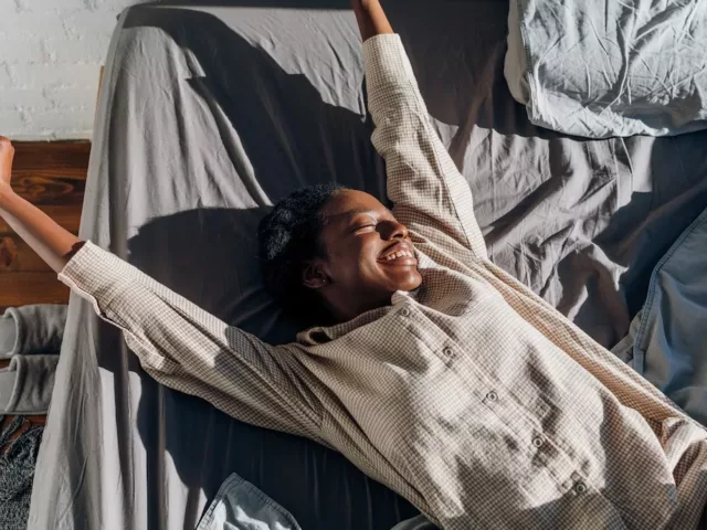 Happy woman stretching in bed after getting beauty sleep