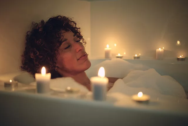 Woman in a warm candlelit bath before bedtime