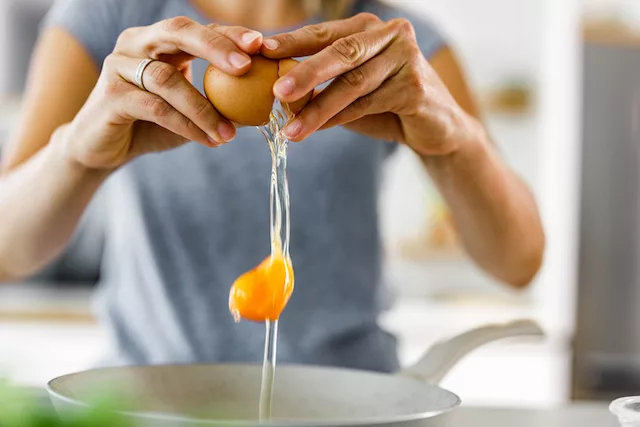 Mujer rompiendo un huevo para el desayuno para perder peso con proteína