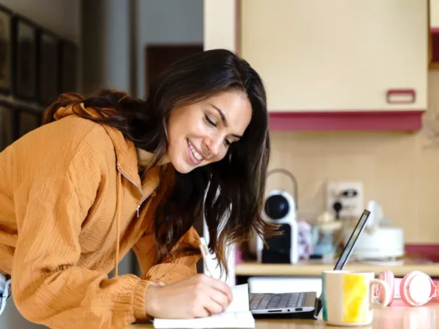 Woman planning her meals in kitchen as she counts macros for weight loss