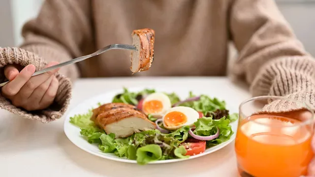 Woman eating a balanced meal to support healthy levels of ghrelin and leptin hormones