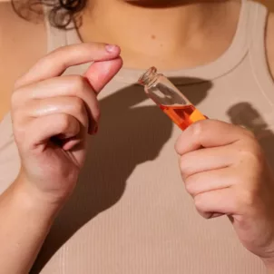 Woman holding an oily skincare product with pore clogging ingredients