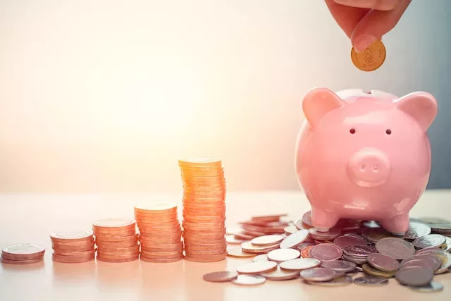 Person putting money into piggy bank for financial wellness