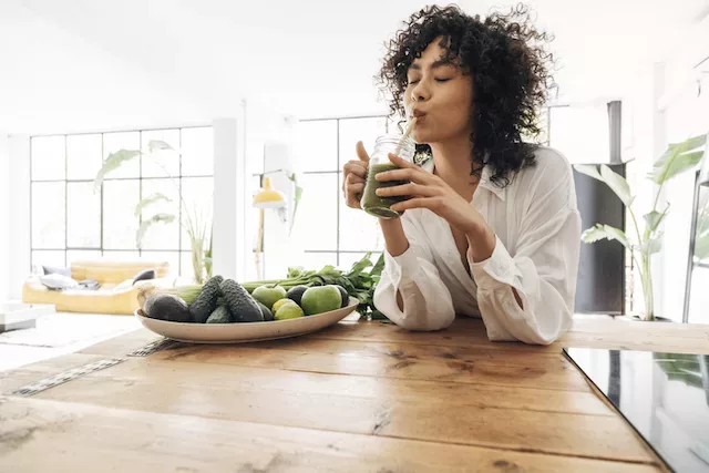 Woman drinking a Detox Smoothie with vegetables and fruit.