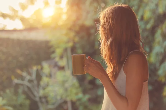 Woman drinking coffee on porch and getting fresh air for self-care